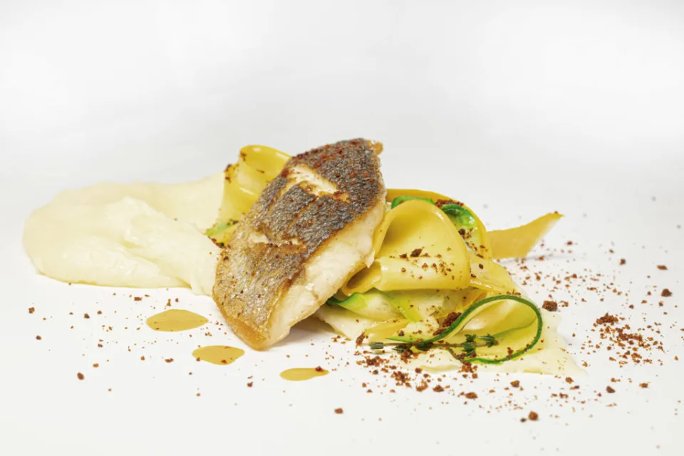 Gebratenes Fischfilet auf Pasta mit Gemüsestreifen und Püree