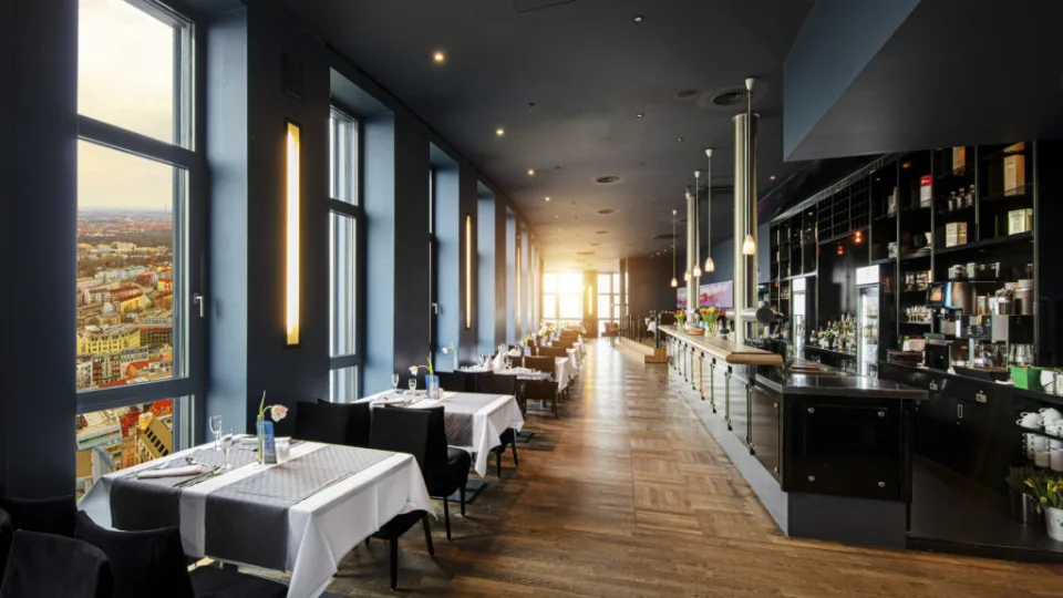 Langer Restaurantraum mit Fensterfront und Bar im Abendlicht