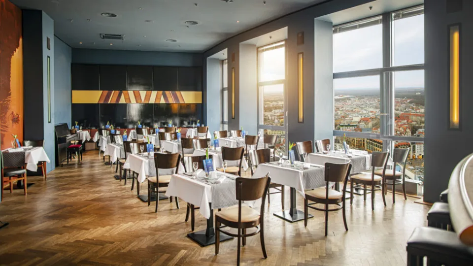 Restaurant mit Holzstühlen, gedeckten Tischen und Panoramafenstern