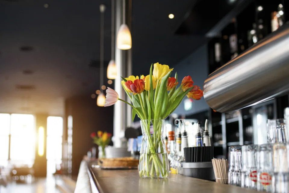 Bar counter with a bouquet of tulips in the restaurant, window front behind
